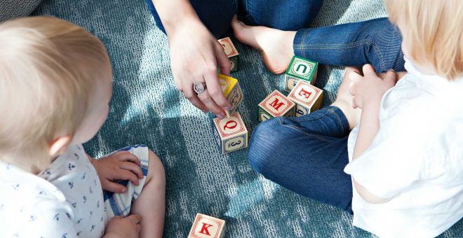 förälder som leker med sina två små barn på golvet